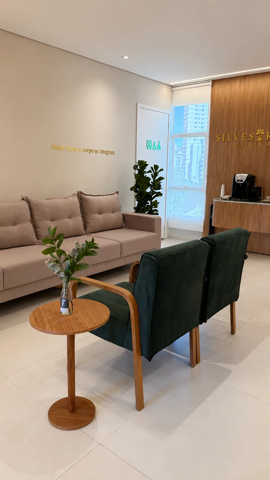 Sala de espera com poltronas verdes e mesa de apoio